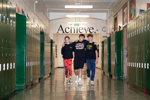Three students walking down a school hall 